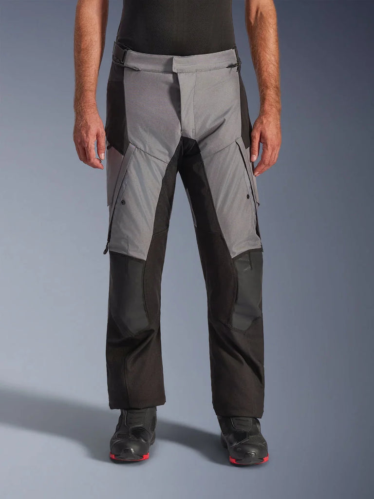 Alpinestars Andes V4 Drystar® Pants, Motorcycle Adventure Touring Pants, Gray and Black, front view worn by a model with black riding boots, featuring reinforced knee patches and thigh cargo pockets, waterproof breathable textile construction for all-weather riding
