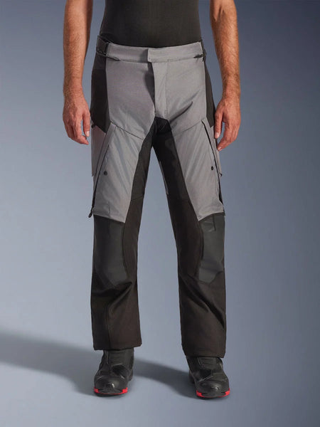 Alpinestars Andes V4 Drystar® Pants, Motorcycle Adventure Touring Pants, Gray and Black, front view worn by a model with black riding boots, featuring reinforced knee patches and thigh cargo pockets, waterproof breathable textile construction for all-weather riding