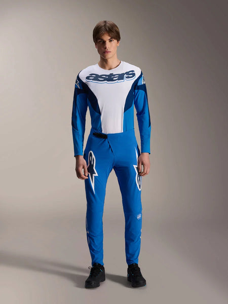 Alpinestars A-Supra Melt Pants, Blue MTB Pants, worn with matching white and blue long-sleeve jersey, featuring white star logo graphics on the thighs, slim performance fit for off-road cycling