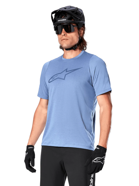Alpinestars A-Dura Dri Astar Jersey Short Sleeve, Infinity Blue, mountain bike jersey with mesh sleeve ventilation and a large chest logo, worn with black helmet, sunglasses, and gloves, technical MTB performance apparel