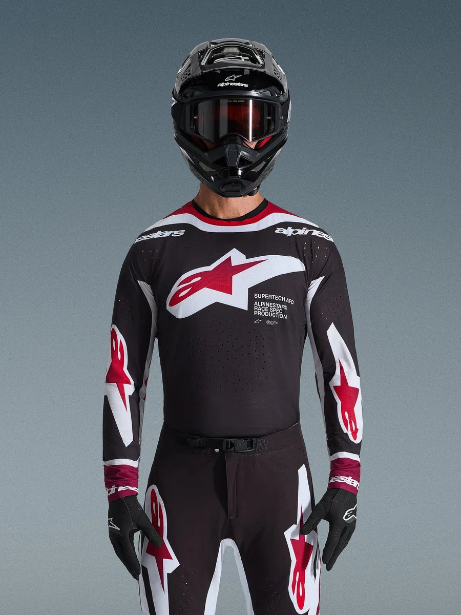 Alpinestars 2026 Supertech AFD Vista Jersey, Motocross Jersey in Black Red and White, shown on a rider with a black helmet, goggles, and gloves, featuring a large chest logo and 'SUPERTECH AFD' branding, professional racing gear for off-road performance