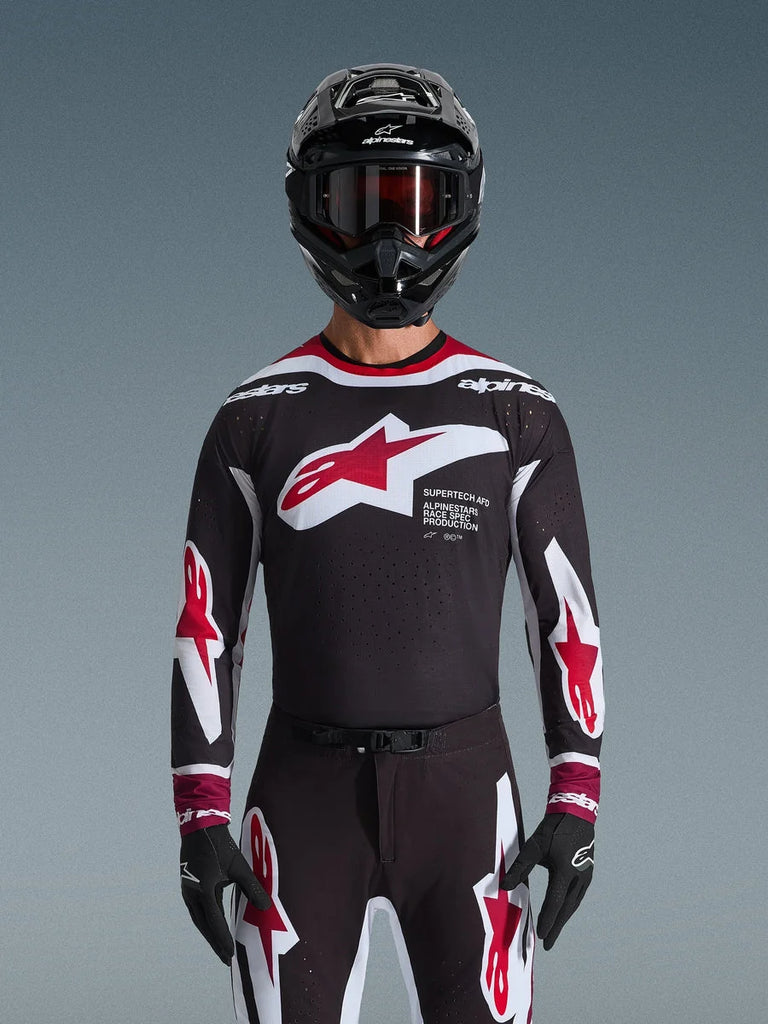 Alpinestars 2026 Supertech AFD Vista Jersey, Motocross Jersey in Black Red and White, shown on a rider with a black helmet, goggles, and gloves, featuring a large chest logo and 'SUPERTECH AFD' branding, professional racing gear for off-road performance