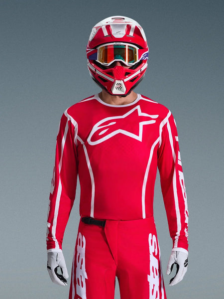 Alpinestars 2026 Fluid Apex Jersey, Motocross Jersey, Red and White, worn by a rider with a matching red and white helmet and orange goggles, featuring a prominent white logo on the chest, athletic fit, part of a coordinated off-road racing gear set