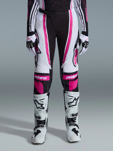 Alpinestars 2026 Woman Stella Techstar Nomur Pants, Motocross Pants, Black White and Fuchsia, worn with matching racing jersey, gloves, and white motocross boots, featuring bold pink graphics and astars logos on the knees, designed for high-level off-road competition.